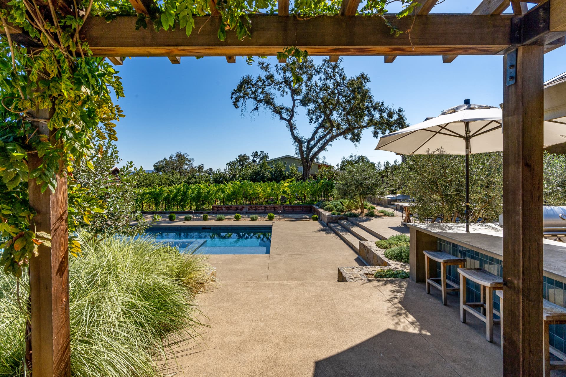 Luxury Napa, CA home with pool, outdoor kitchen and vineyard views under a clear blue sky