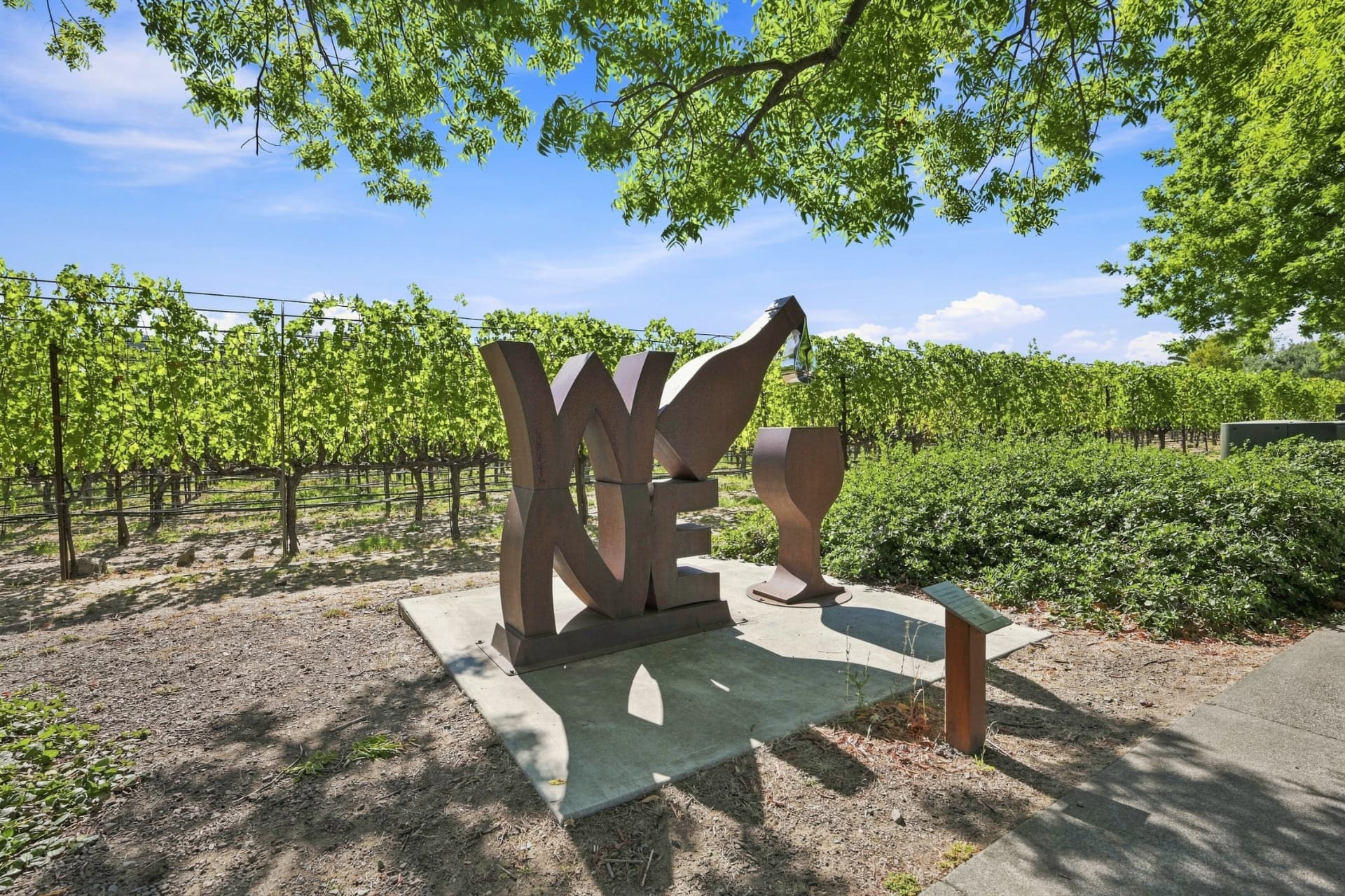 Corten steel WINE sculpture set against vineyard rows in Yountville